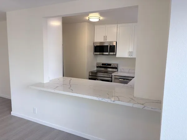 a kitchen with stainless steel appliances a microwave a stove and white cabinets