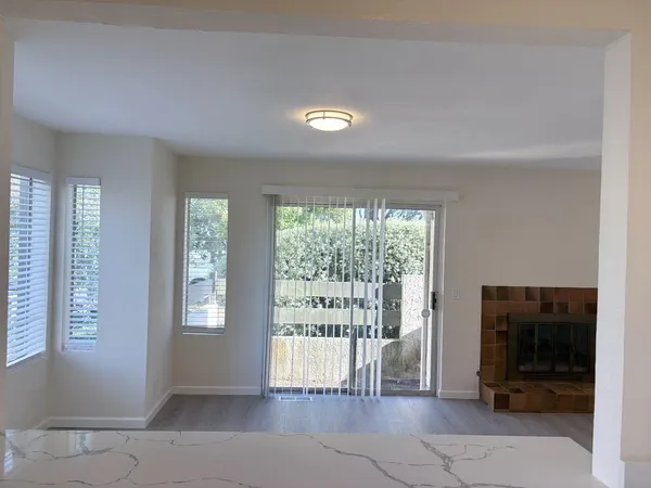 wooden floor in an empty room with a fireplace and a window
