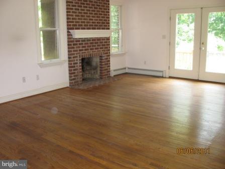 13923 Sunnybrook Road Phoenix, MD 21131 - Photo 3 of 10 an empty room with wooden floor fireplace and windows
