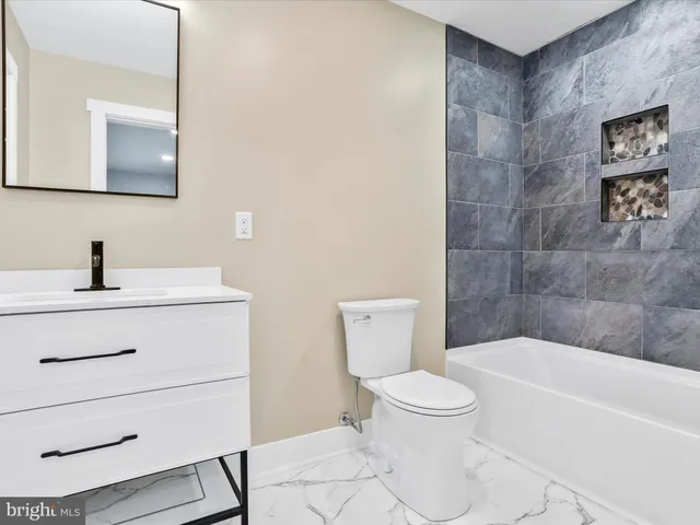 a bathroom with a toilet a sink a mirror and bathtub