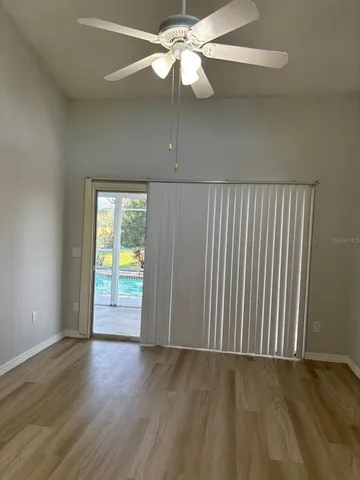 an empty room with wooden floor fan and windows