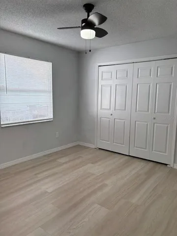 an empty room with wooden floor ceiling fan and windows