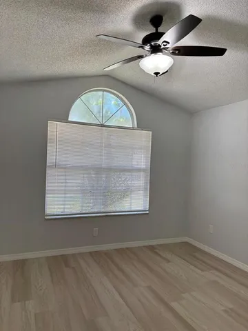 an empty room with a window and a ceiling fan