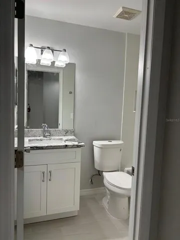 a bathroom with a granite countertop sink vanity mirror and toilet
