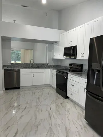 a kitchen with granite countertop a sink stainless steel appliances and white cabinets