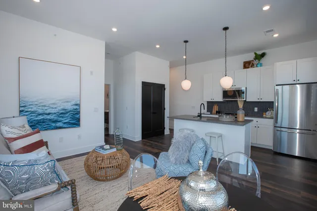 a large kitchen with cabinets a refrigerator a bed and chairs