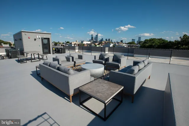 a roof deck with couches and potted plants with sky view