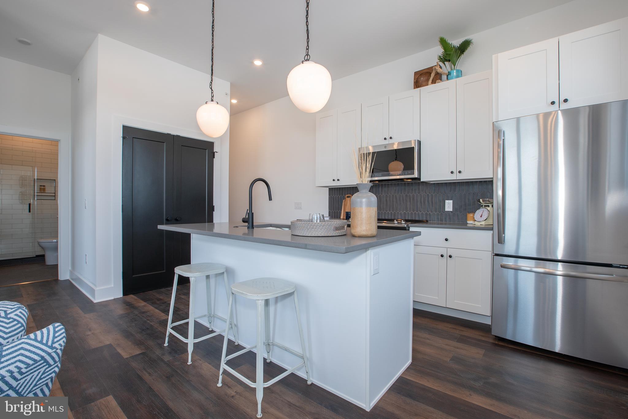 2940 West Thompson Street, Unit 302 Philadelphia, PA 19121 - Photo 26 of 43 a kitchen with stainless steel appliances granite countertop a refrigerator a stove a sink dishwasher and a refrigerator with wooden floor