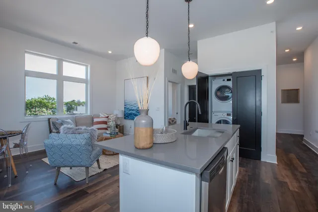 a kitchen with a sink dishwasher a dining table and chairs with wooden floor
