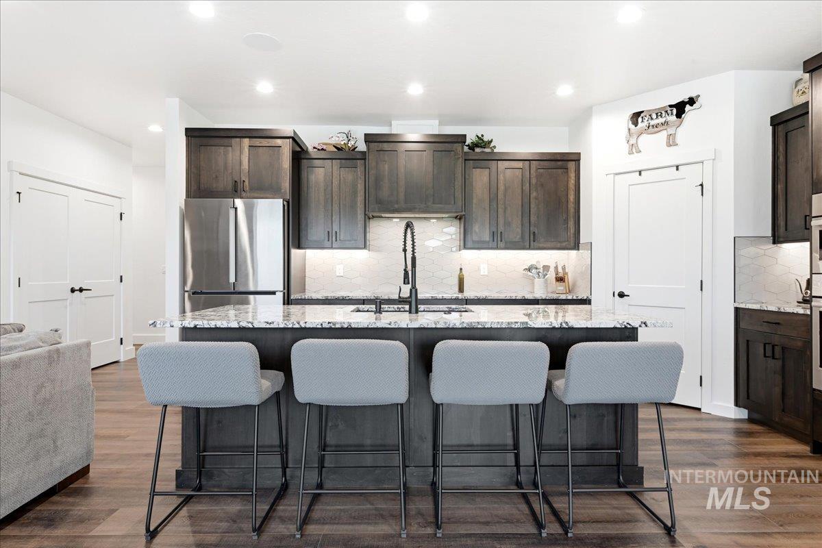 13152 Hawks Bay Road Donnelly, ID 83615 - Photo 7 of 29 Modern kitchen featuring an island with stone countertops, dark wood-finish cabinetry, stainless steel appliances, and wood-finish flooring
