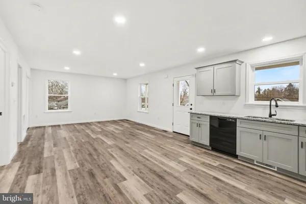 a large kitchen with kitchen island a sink wooden floor and stainless steel appliances