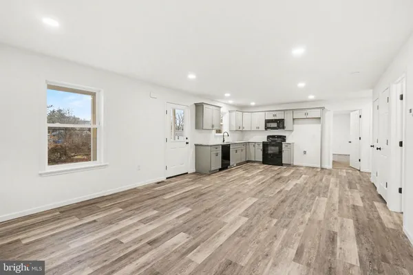 a view of empty room with kitchen and window