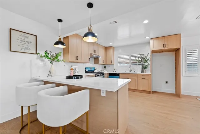 a kitchen with stainless steel appliances granite countertop a sink a stove a refrigerator cabinets and chairs