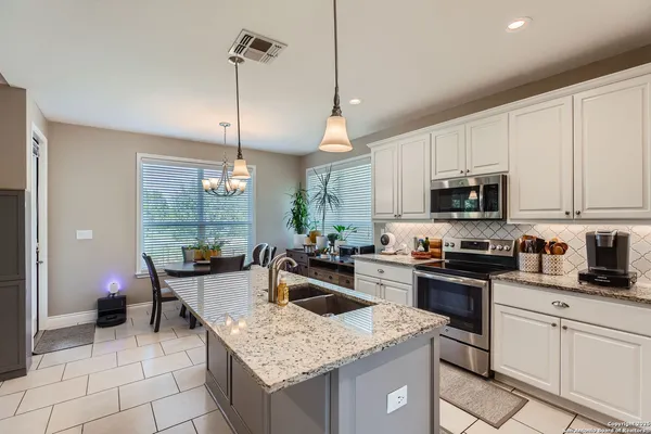 a kitchen with granite countertop a sink a counter top space appliances and cabinets