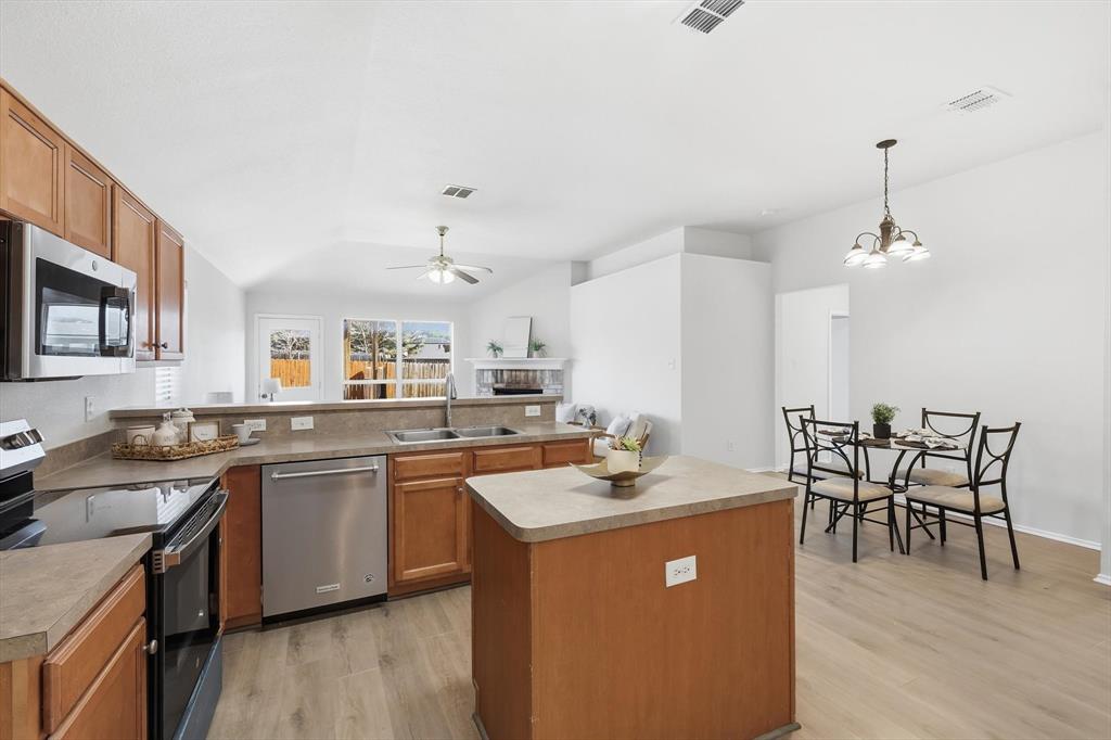 121 Kings Way Drive Rhome, TX 76078 - Photo 14 of 38 a kitchen with stainless steel appliances granite countertop a sink a stove a dining table and chairs