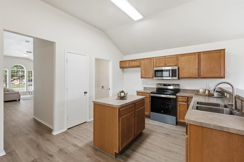 121 Kings Way Drive Rhome, TX 76078 - Photo 8 of 38 a kitchen with stainless steel appliances granite countertop a stove top oven a sink dishwasher and a refrigerator with wooden floor