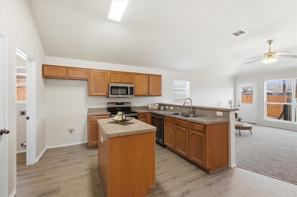 121 Kings Way Drive Rhome, TX 76078 - Photo 9 of 38 a kitchen with stainless steel appliances granite countertop a stove top oven a sink dishwasher and a refrigerator with wooden floor