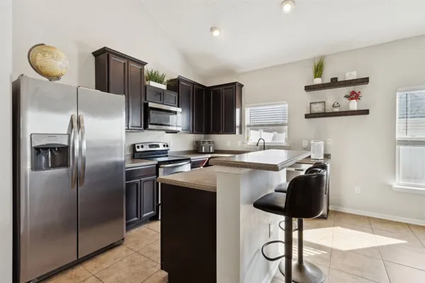 a kitchen with stainless steel appliances granite countertop a stove top oven a sink a dining table and chairs with wooden floor