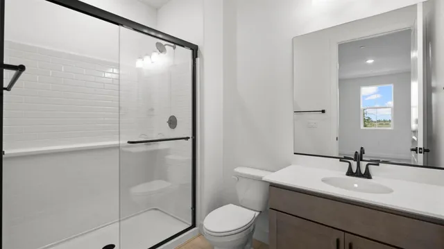 a bathroom with a shower sink vanity mirror and toilet