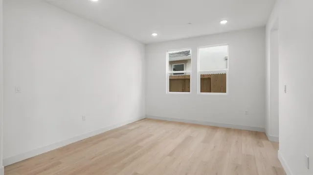a view of empty room with wooden floor and fan