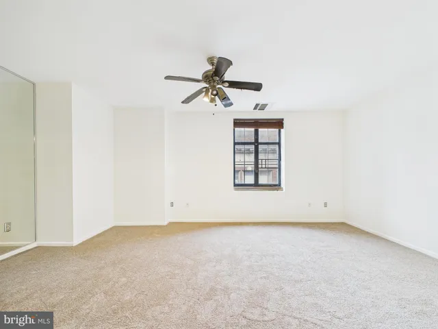 an empty room with windows and fan