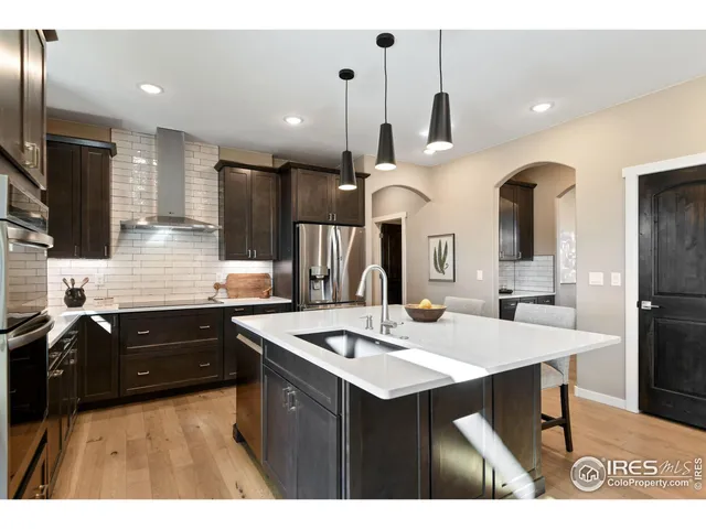 a kitchen with stainless steel appliances kitchen island granite countertop a sink a stove and refrigerator