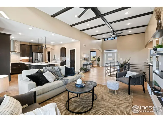 a living room with furniture kitchen view and a wooden floor