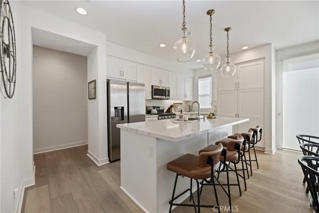 a kitchen with kitchen island a dining table chairs stainless steel appliances and cabinets