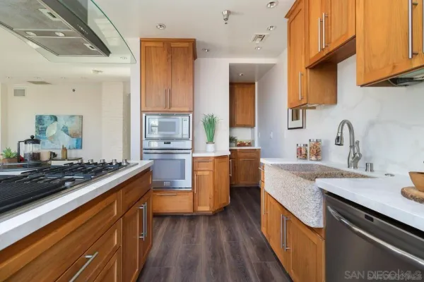 a kitchen with stainless steel appliances a stove a sink dishwasher and cabinets with wooden floor