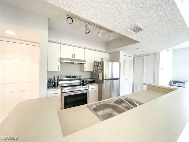 a kitchen with stainless steel appliances granite countertop a stove refrigerator and a sink
