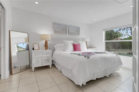 a bedroom with a bed a flat tv screen and a potted plant