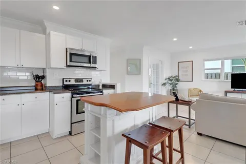 a kitchen with stainless steel appliances granite countertop a sink a stove a microwave a dining table and chairs