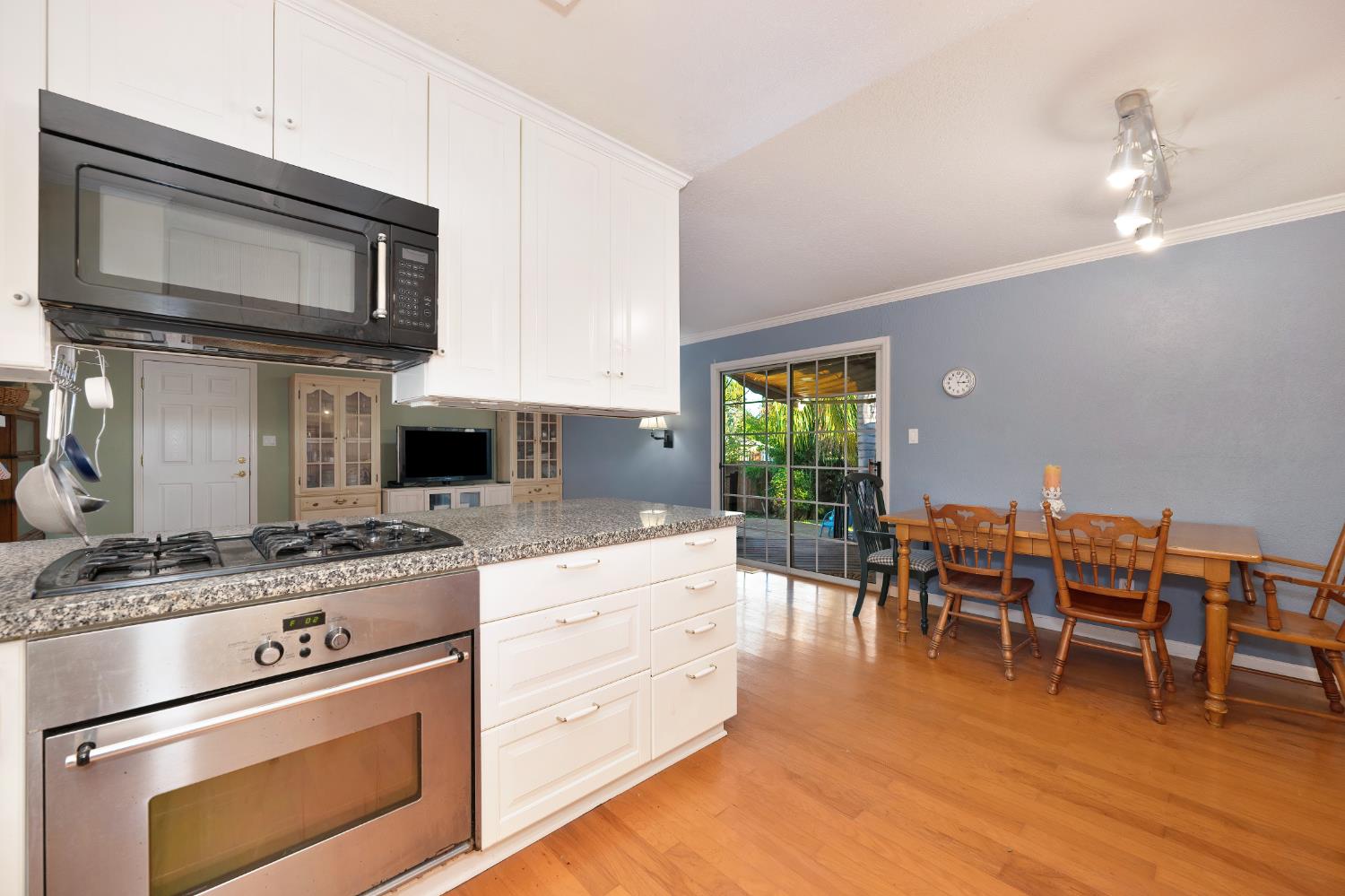 6430 Sandstone Street Carmichael, CA 95608 - Photo 12 of 39 a kitchen with stainless steel appliances granite countertop a stove top oven a sink dishwasher a dining table and chairs with wooden floor