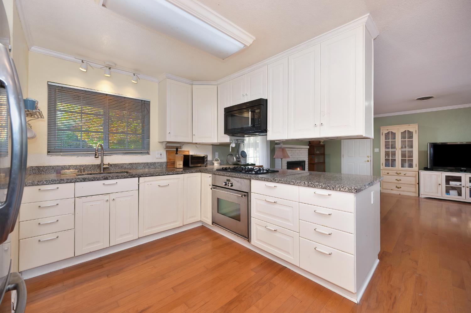 6430 Sandstone Street Carmichael, CA 95608 - Photo 10 of 39 a kitchen with stainless steel appliances granite countertop a stove top oven a sink a dining table and chairs with wooden floor