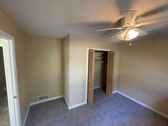 an empty room with closet and a chandelier fan