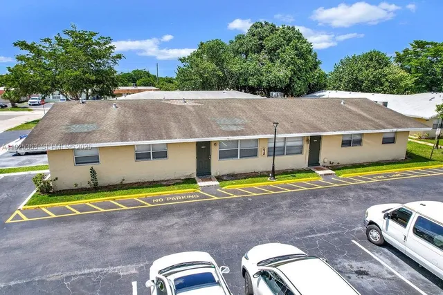a view of pool with lawn chairs and large trees