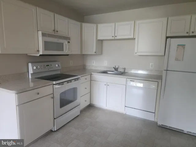 a kitchen with white cabinets stainless steel appliances and sink