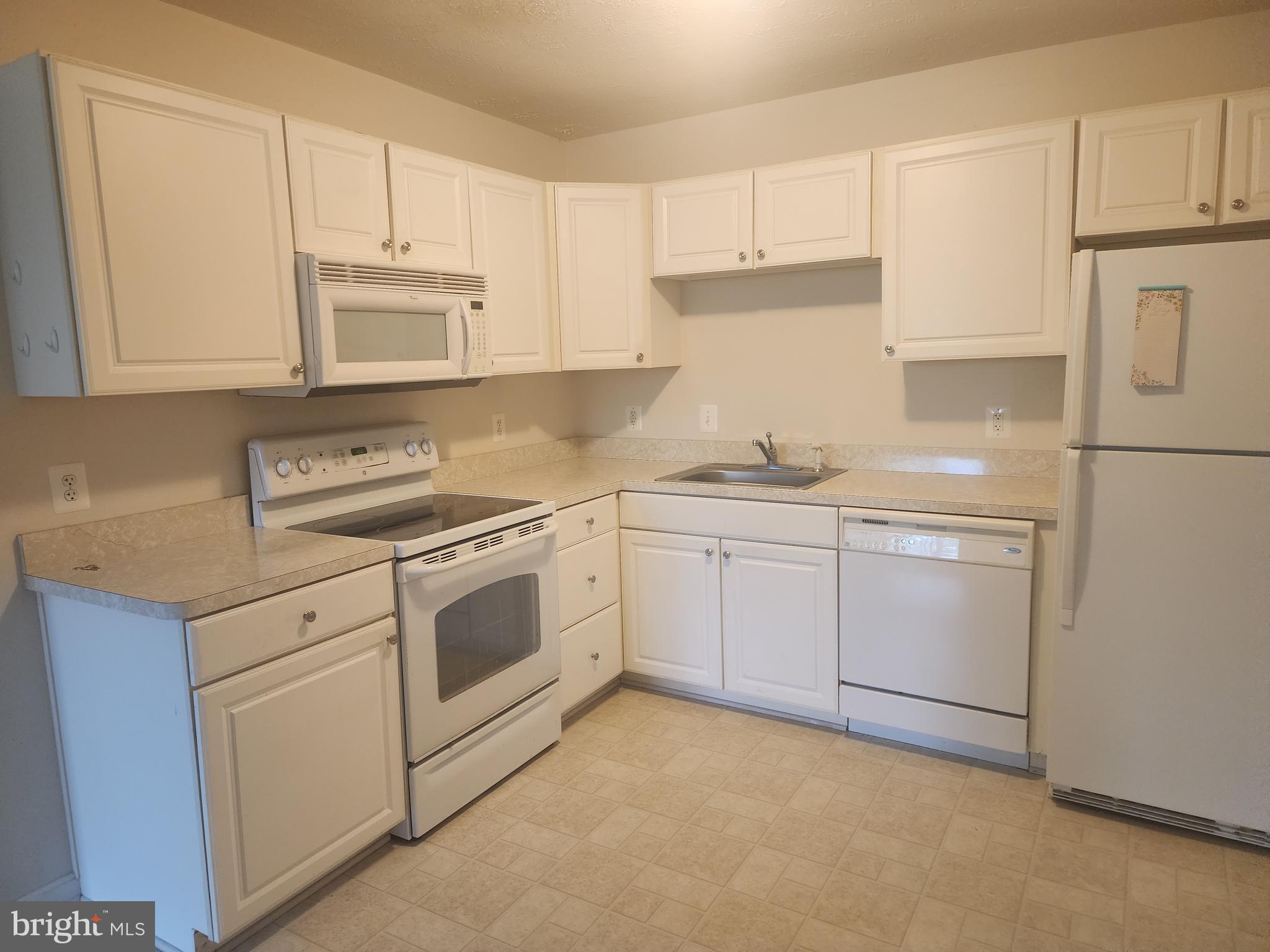36548 Notley Hall Road, Unit A Chaptico, MD 20621 - Photo 2 of 8 a kitchen with white cabinets sink and white appliances