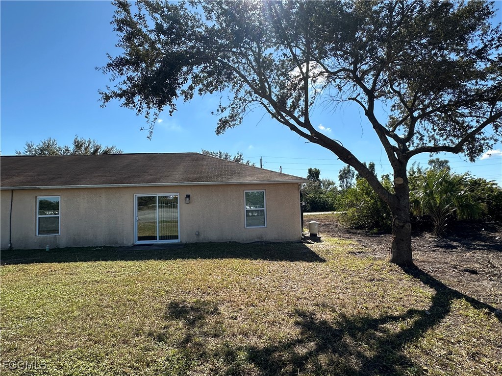 2411 Park Road, Unit 2409 Lehigh Acres, FL 33971 - Photo 20 of 20 a backyard of a house with large trees and covered with tall trees