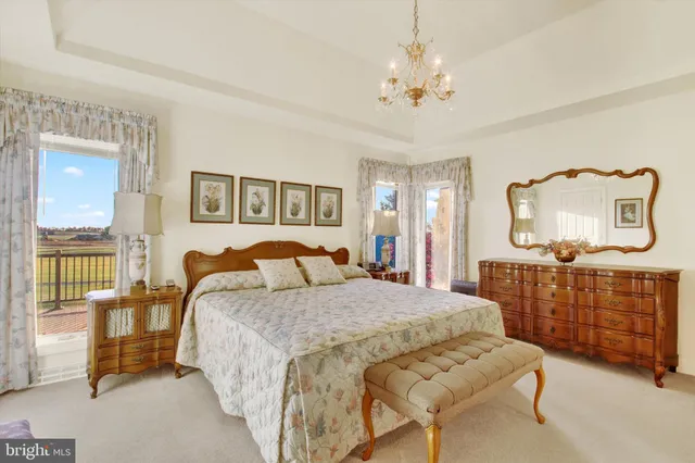 a bedroom with a bed a chandelier and dresser