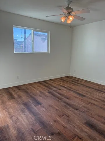 an empty room with wooden floor and a ceiling fan