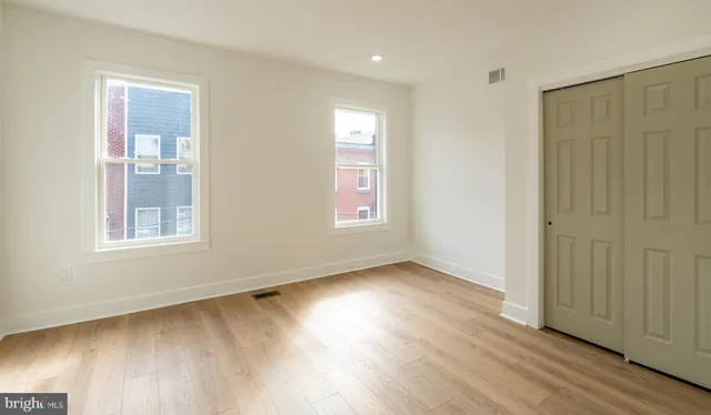 an empty room with wooden floor and windows