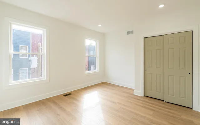 an empty room with wooden floor and windows