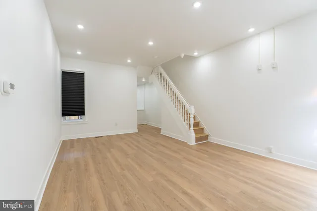 an empty room with wooden floor and stairs