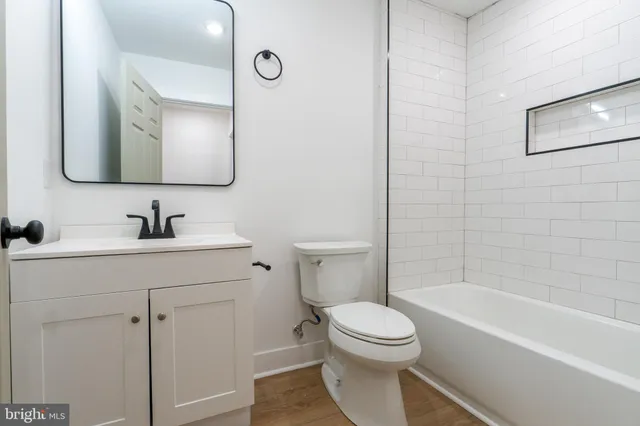 a view of a hallway with wooden floor and a bathroom