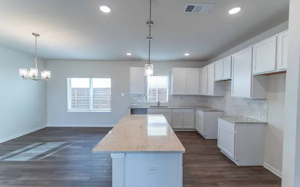 a kitchen with kitchen island granite countertop a stove a sink a center island and a window