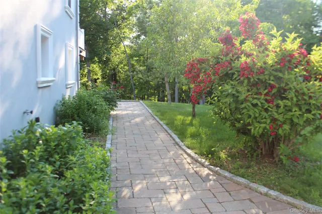 a view of a pathway with flower plants and wooden fence