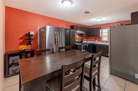 a kitchen with stainless steel appliances a dining table chairs and a refrigerator