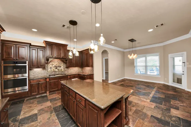 a kitchen with a stove a refrigerator a sink and chairs