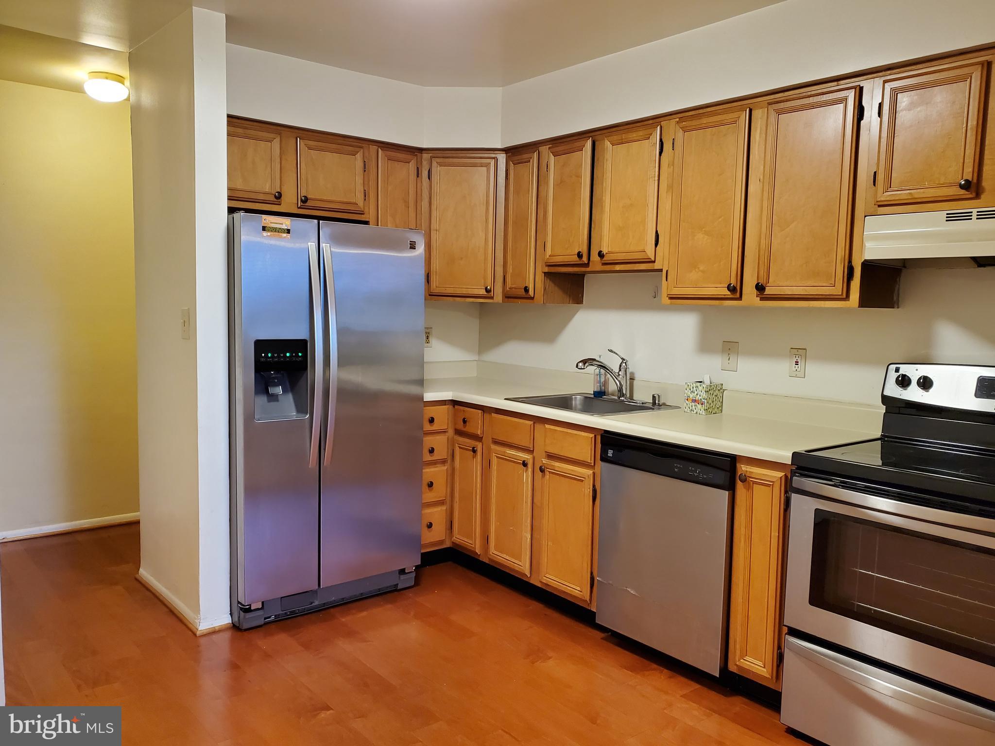 1002 Spring Gate Road, Unit 2C Baltimore, MD 21228 - Photo 4 of 12 a kitchen with stainless steel appliances granite countertop a refrigerator a sink and dishwasher a stove with wooden floor